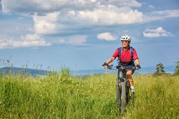 nice active senior woman riding her electric mountain bikeon Salmas summit in Oberstaufen, Allgaeu...