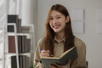 an Asian businesswoman is writing detail from the last meeting, there is a beautiful employee is...