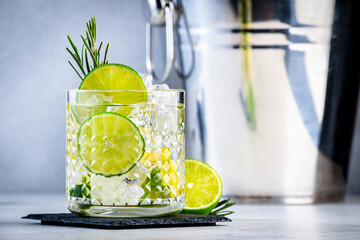 Gin tonic with rosemary cocktail drink with dry gin, bitter tonic, lime and ice. Gray background