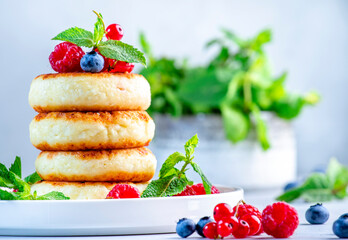 Thick pancakes with cottage cheese and berries with mint for yummy breakfast. Gray table background