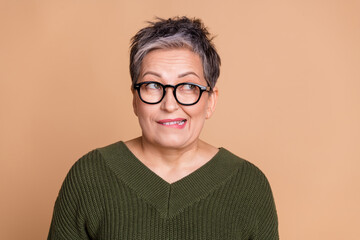 Photo of excited woman with short hairdo dressed khaki sweater in glasses biting lip look empty...