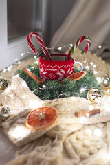 Christmas composition: Red cup with candy cane, White knitted scarf, garland, citrus chips.