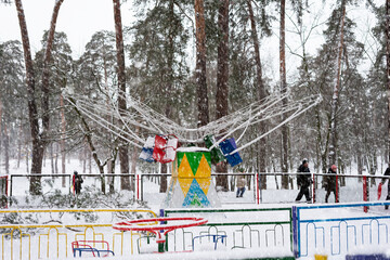 Non-working children's carousel in a snowy forest.