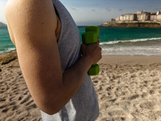Man Holding Dumbbells on Beach Side View
