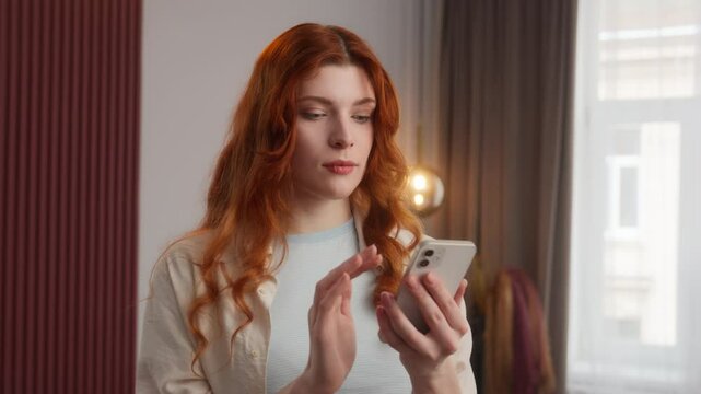 Happy Caucasian woman girl model scroll screen typing mobile phone smartphone at home apartment shock good message pleasantly surprised lady female smile winning rejoice success victory positive news