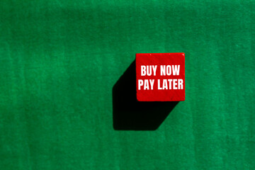 Buy now pay later message written on red wooden cube with green background. Conceptual buy now pay...