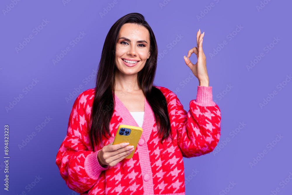 Poster photo of adorable lovely girl wear pink cardigan showing okey sign texting modern gadget isolated pu