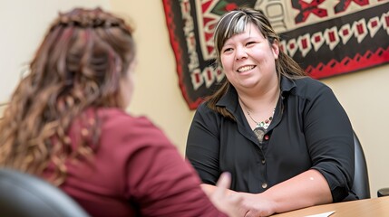 Generational Bridge: A half Native American woman, with a kind smile and silver streaks in her hair, sits across from a young woman, seemingly sharing advice or a story. Both women are dressed 