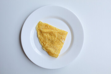 Omelet folded into a triangle, on white plate, isolated on white background, flat lay or top view