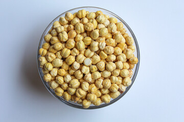 Chickpeas in glass transparent bowl, isolated on white background, flat lay or top view