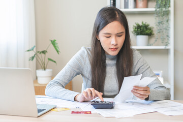 Business financial concept, owe asian young woman crisis and stressed, calculate expense, cost or budget on table at home from invoice or bill have no money to pay mortgage or loan, debt bankruptcy.