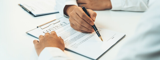 Business executive signing contract agreement document on the bale with the help from company...