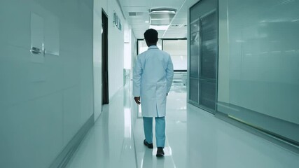 An African American doctor in a white coat and with a stethoscope around his neck walks through the hospital.
Concept: healthcare and medical services