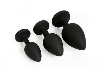Set of black silicone anal plugs lie in line. Butt plugs on a white abstract background. Sex toys...