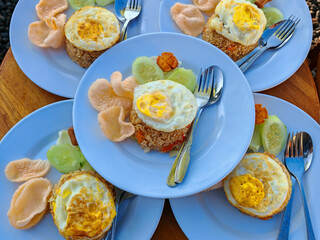 Fried rice with fried egg, sausage, cucumber and crackers. Served in the morning, selected focus blurred background