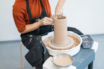Close-up of a potter's hands making a ceramic vase on a potter's wheel. 