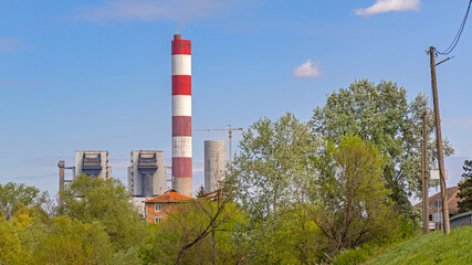 Red and White Chimney at Thermal Power Plant Facility Spring Day Blue Sky