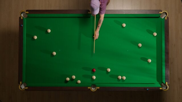 Top view shot of russian billiard green cloth table with red and white balls, person hitting the balls with cue.