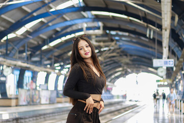 Fototapeta premium Young woman standing on a metro station platform and waiting for a metro train. People travel in public transport concept.