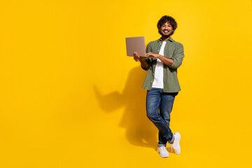 Photo of expert manager mexican confident successful freelance specialist in khaki shirt using netbook isolated on yellow color background