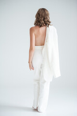 Fototapeta premium Elegant woman in white suit on white background