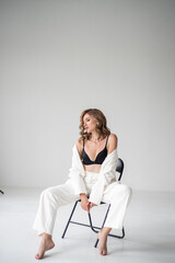 young beautiful woman in formal clothes posing on a chair in studio
