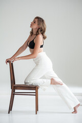 Fototapeta premium young beautiful woman in formal clothes posing on a chair in studio