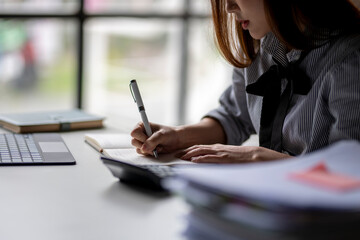 A woman is writing in a notebook with a pen
