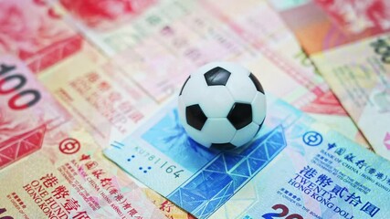 Soccer ball on stack of Hongkong dollars - Powered by Adobe