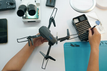Top view of repairman checking the work of drone ith special tool