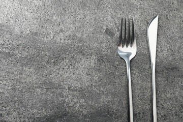 Stylish silver cutlery on grey table, top view. Space for text