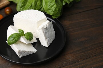 Fresh ricotta (cream cheese) and basil on wooden table, closeup. Space for text