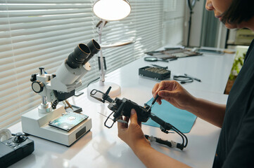 Master using tool to repair broken drone at her workplace in workshop