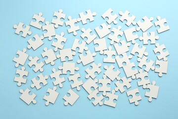 White puzzle pieces on light blue background, top view