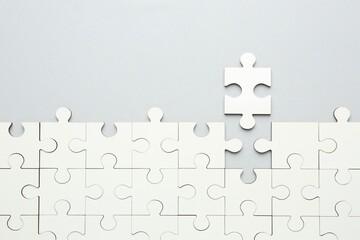 White puzzle pieces on grey background, top view. Space for text
