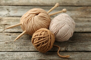 Skeins of soft yarn and knitting needles on wooden table