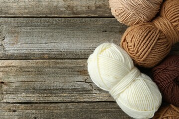 Skeins of different yarn on wooden table, flat lay with space for text. Knitting material