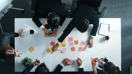 Top down aerial view of diverse business people writing marketing idea or taking a note on sticky notes. Professional executive manager group brainstorm financial plan at meeting room. Directorate.
