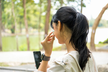 Fototapeta premium Young woman sitting and listening to music at the park.