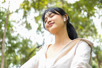 Naklejka premium Young woman sitting and listening to music at the park.