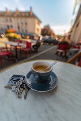 A cup of expresso coffee on an outside table in a cafe with glasses, key ring and mobile phone, shot with a very wide angle and shallow depth of field