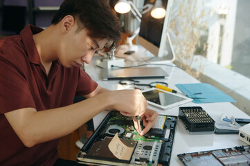 Technician using screwdriver to repair motherboard of laptop