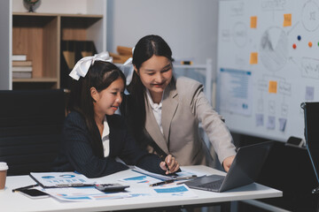 Two young Asian business woman talk, consult, discuss working with new startup project idea presentation analyze plan marketing and investment in the office.