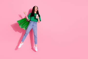 Full length photo of charming positive woman wear green t-shirt jumping online shopping modern device empty space isolated pink color background