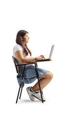 Teenage girl sitting in a school chair and using a laptop computer