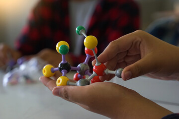 Hand holding a Simulate Shape of covalent molecules on a gray and white background....