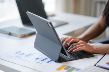 Businesswoman is working on a tablet computer, analyzing financial data and charts in a bright and modern office setting