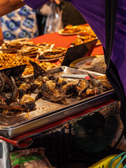 A vendor sells fried fish at a street food market