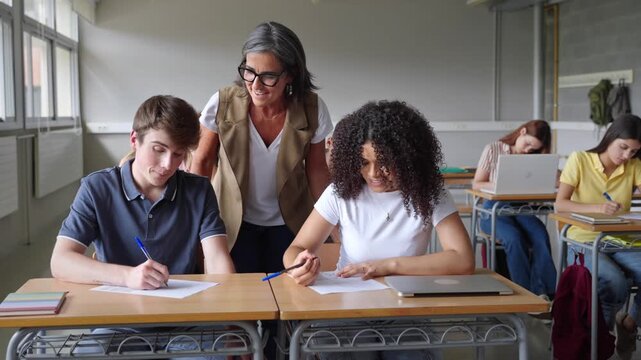 Friendly teacher helping students learning writing exercise at College High School