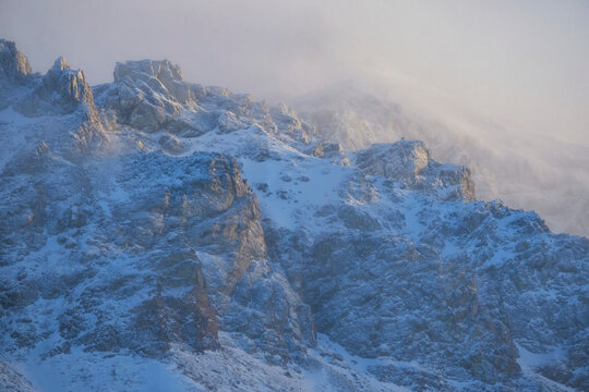 Winter sets in the Yukon as misty clouds cover the craggy mountainside surrounding Annie Lake come alive in sublime snow and light; Whitehorse, Yukon, Canada